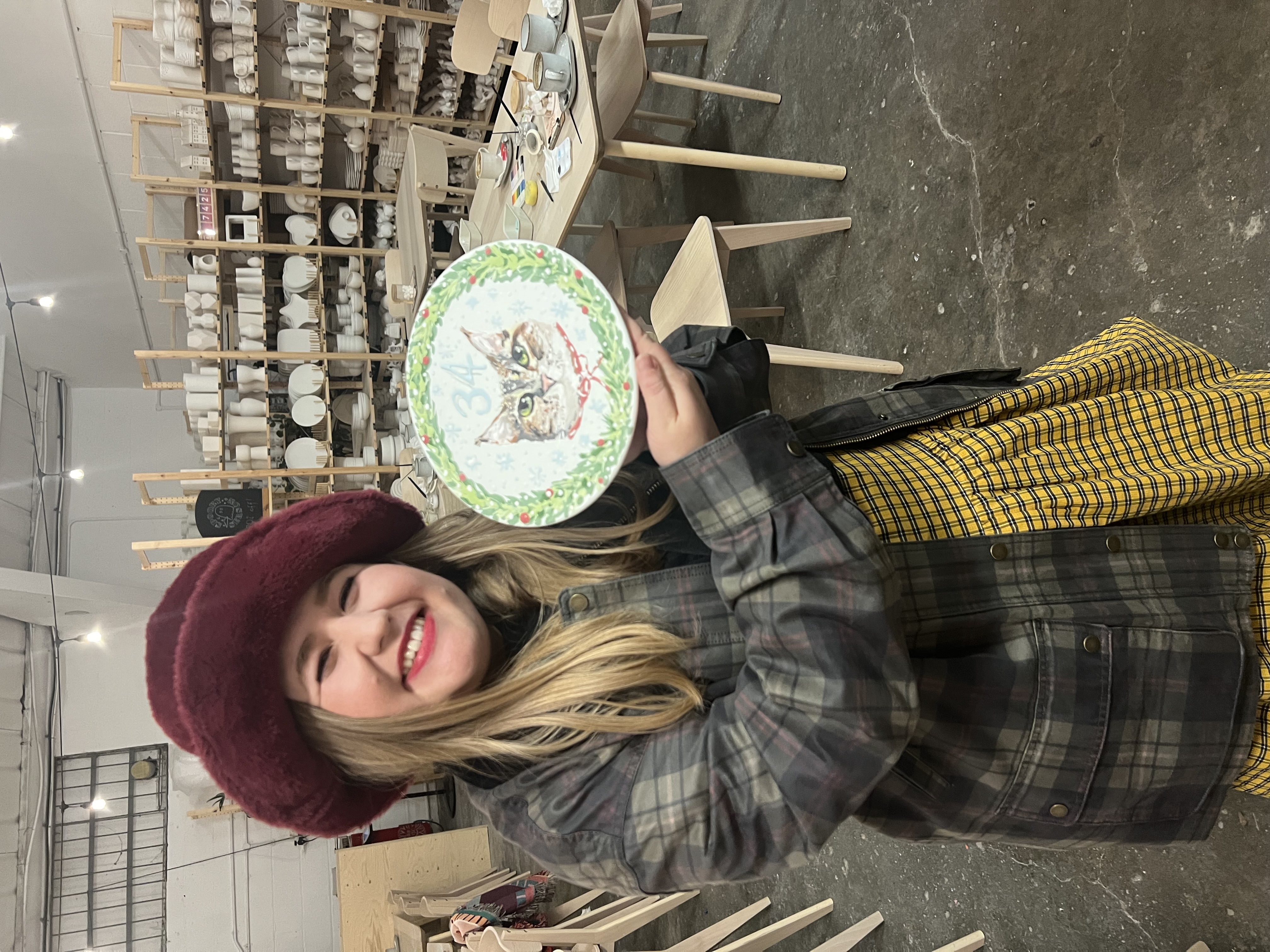 A guest proudly holding a hand-painted plate she made at a creative celebration